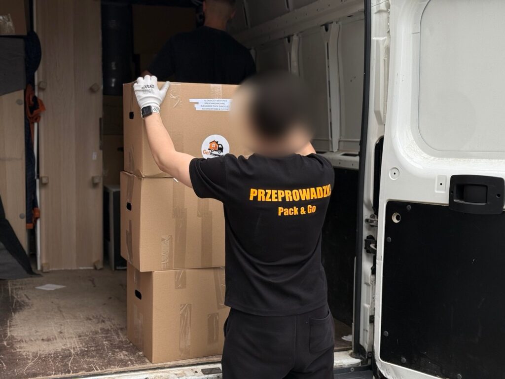 Pracownik firmy przeprowadzkowej pakujący kartony do busa podczas przeprowadzki mieszkania w Warszawie
